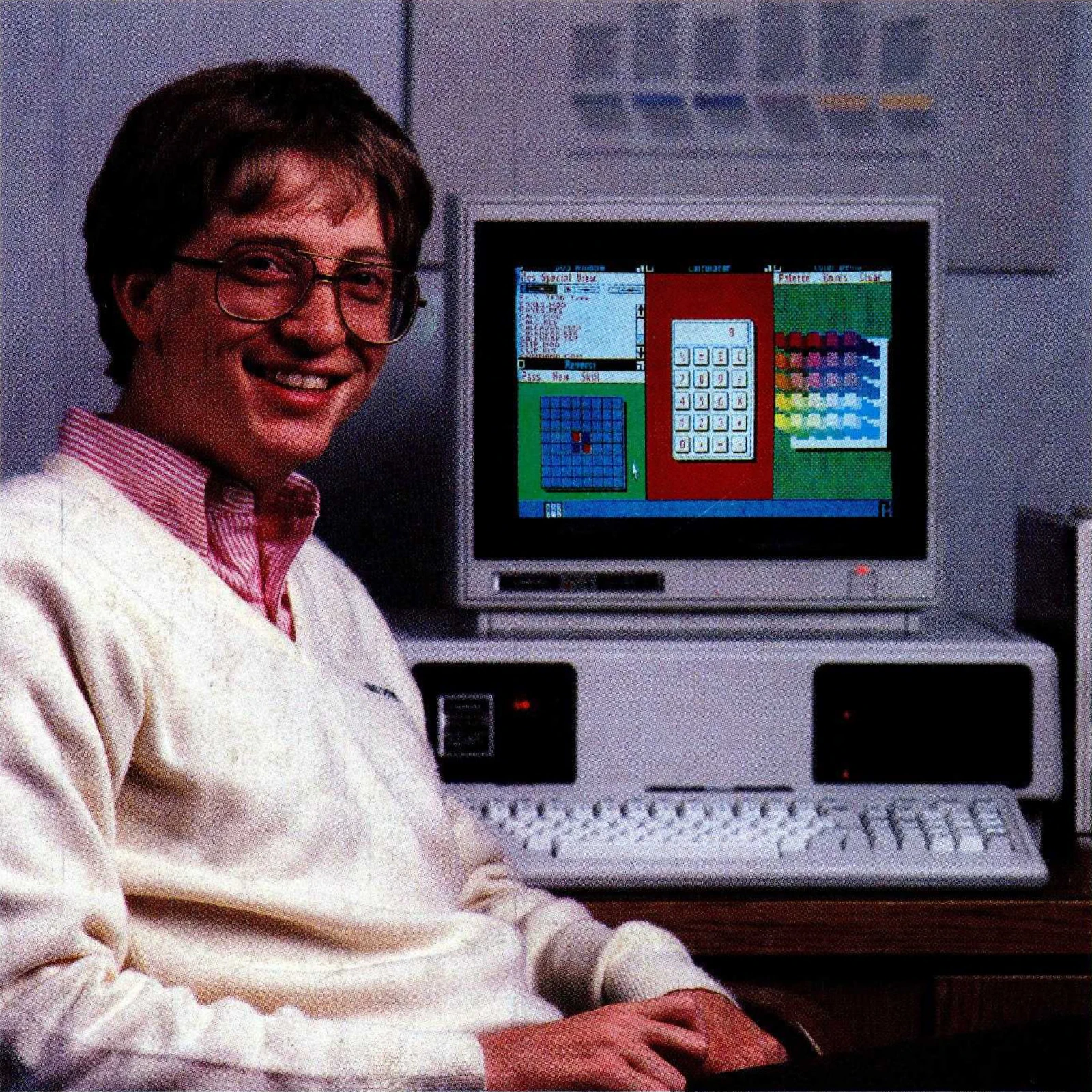 Bill Gates seated beside a Tandy 2000 displaying an early version of Windows in a 1984 magazine advertisement photograph.